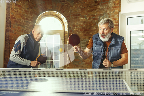 Image of Senior men playing table tennis in workplace, having fun