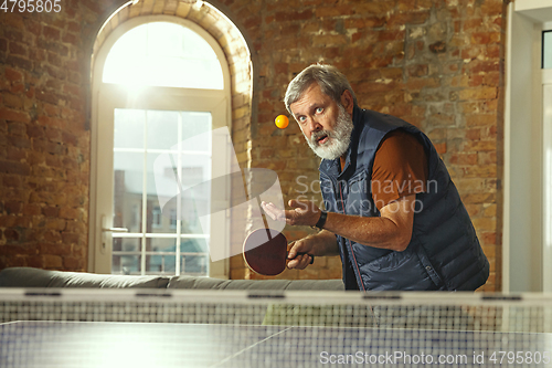 Image of Senior man playing table tennis in workplace, having fun