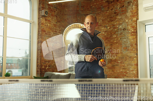 Image of Senior man playing table tennis in workplace, having fun