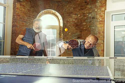 Image of Senior men playing table tennis in workplace, having fun