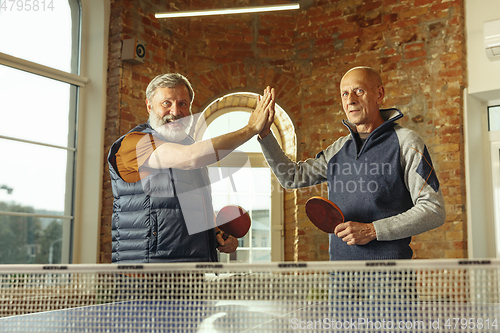 Image of Senior men playing table tennis in workplace, having fun