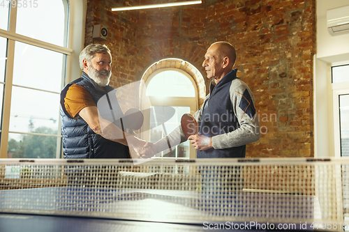 Image of Senior men playing table tennis in workplace, having fun