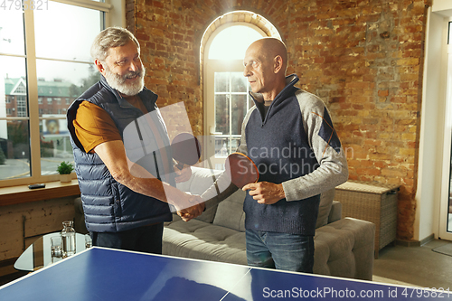 Image of Senior men playing table tennis in workplace, having fun