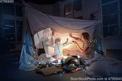 Image of Family sitting in a teepee, reading stories with the flashlight