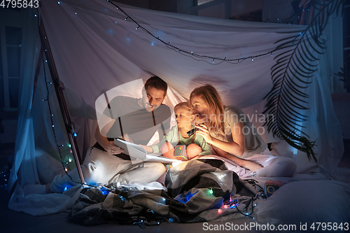 Image of Family sitting in a teepee, reading stories with the flashlight