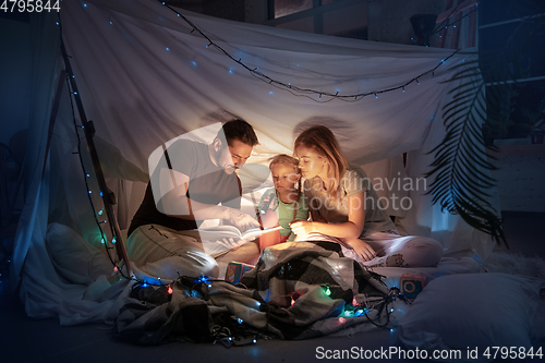 Image of Family sitting in a teepee, reading stories with the flashlight