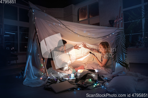 Image of Family sitting in a teepee, having fun with the flashlight