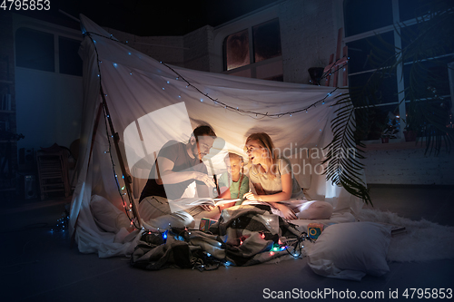 Image of Family sitting in a teepee, reading stories with the flashlight