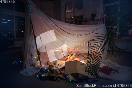 Image of Little girl lying in a teepee, playing with the flashlight