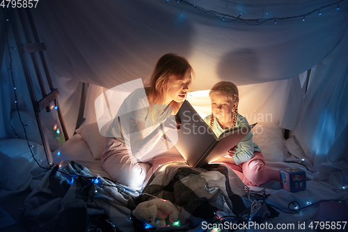 Image of Mother and daughter sitting in a teepee, reading stories with the flashlight