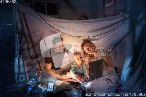 Image of Family sitting in a teepee, having fun with the flashlight