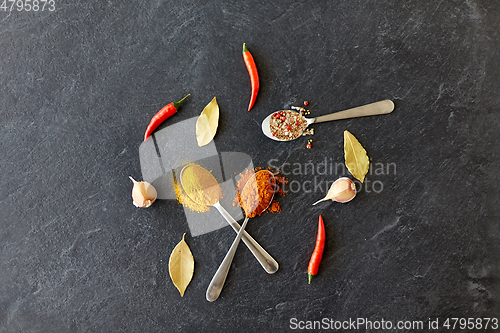 Image of spices, chili pepper, bay leaf and garlic on stone