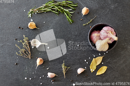 Image of garlic in bowl and rosemary on stone surface