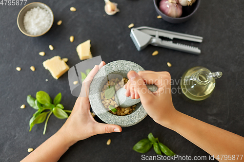 Image of hands grinding pine nuts in mortar and pestle