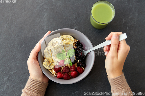 Image of hands of woman eating cereal breakfast with spoon