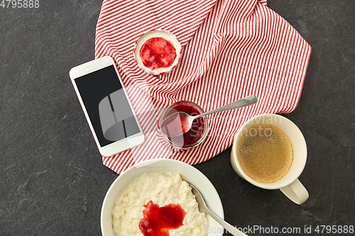 Image of porridge with jam, spoon, coffee and phone