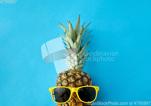 Image of pineapple in yellow sunglasses on blue background