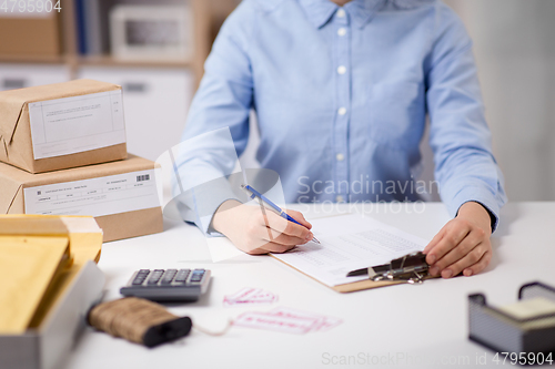 Image of woman with clipboard and parcels at post office