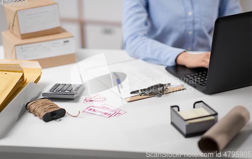 Image of woman with laptop and clipboard at post office