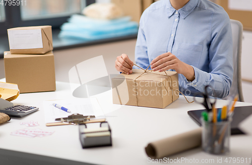 Image of woman packing parcel and tying rope at post office