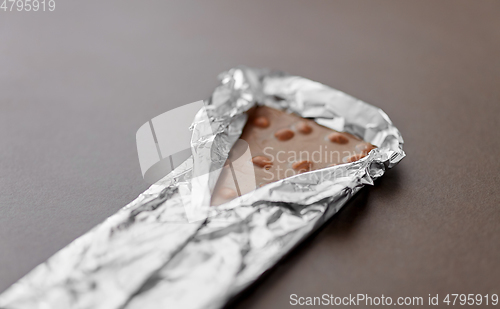 Image of close up of milk chocolate bar with nuts in foil