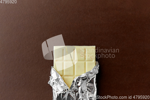 Image of white chocolate bar in foil wrapper on brown