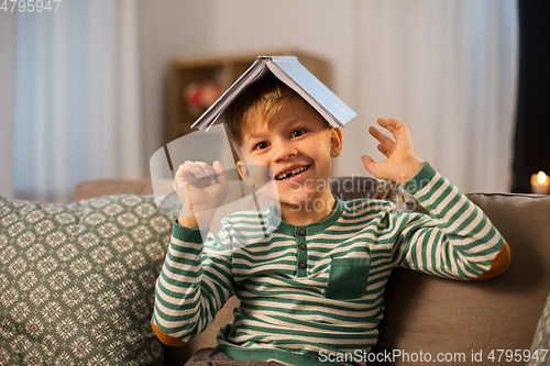 Image of happy little boy with book having fun at home