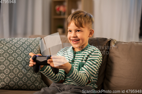 Image of little boy with gamepad playing video game at home