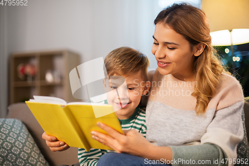 Image of happy mother and son reading book sofa at home