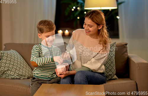 Image of mother and little son with piggy bank at home