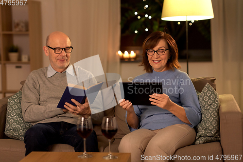 Image of senior couple with book and tablet pc at home