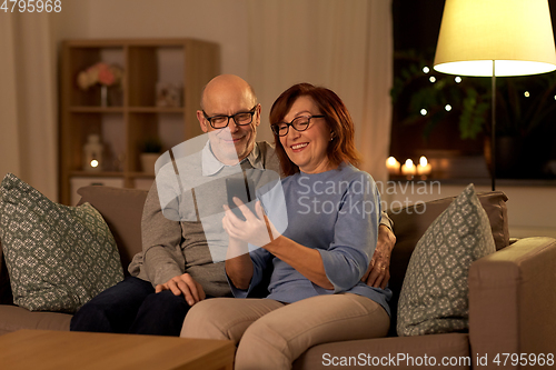 Image of happy senior couple with smartphone at home