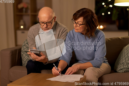 Image of senior couple with papers and calculator at home