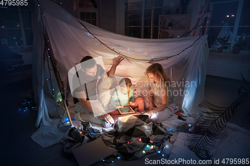 Image of Family sitting in a teepee, having fun with the flashlight