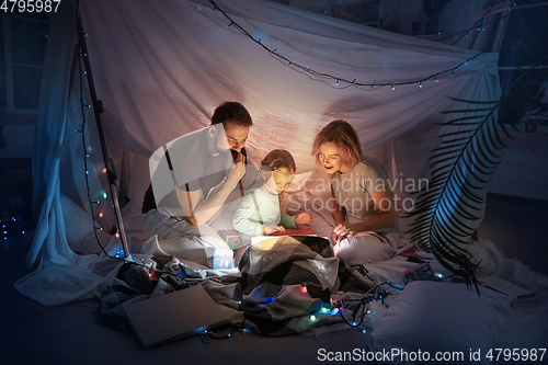 Image of Family sitting in a teepee, reading stories with the flashlight