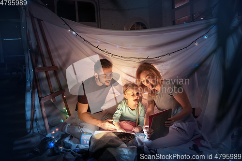 Image of Family sitting in a teepee, having fun with the flashlight