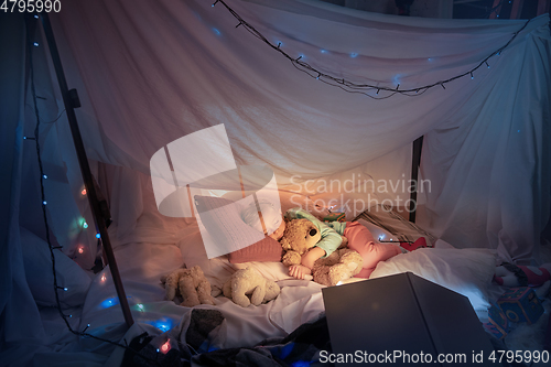 Image of Little girl lying in a teepee, sleeping with the flashlight