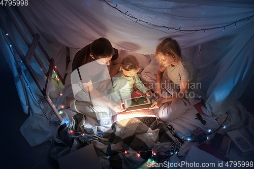 Image of Family sitting in a teepee, reading stories with the flashlight