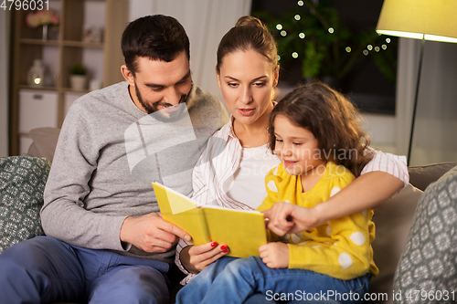 Image of happy family reading book at home at night