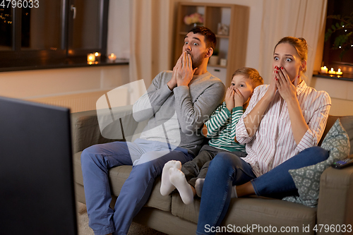 Image of scared family watching tv at home at night