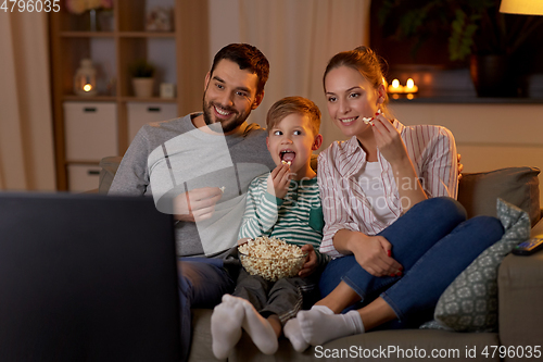 Image of happy family with popcorn watching tv at home