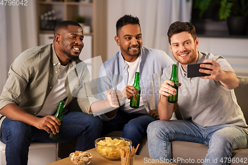Image of male friends with smartphone taking selfie at home