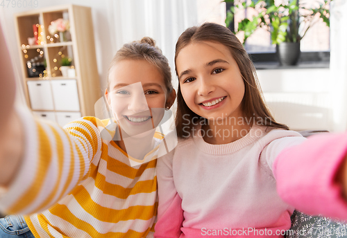 Image of happy teenage girls taking selfie at home