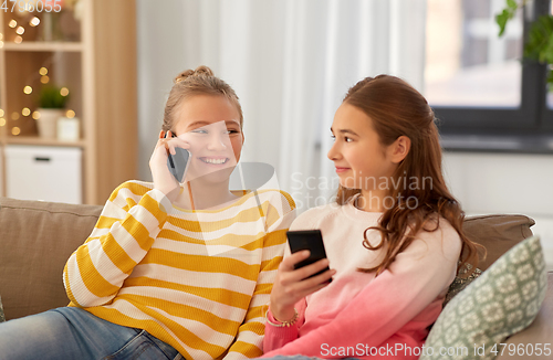 Image of happy teenage girls with smartphones at home