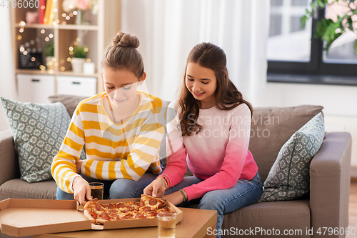 Image of happy teenage girls eating takeaway pizza at home