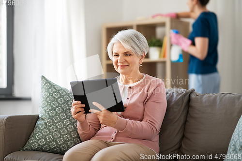 Image of old woman with tablet pc and housekeeper at home