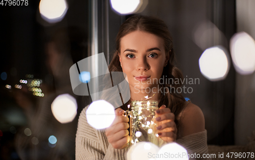 Image of woman with christmas garland lights in glass mug