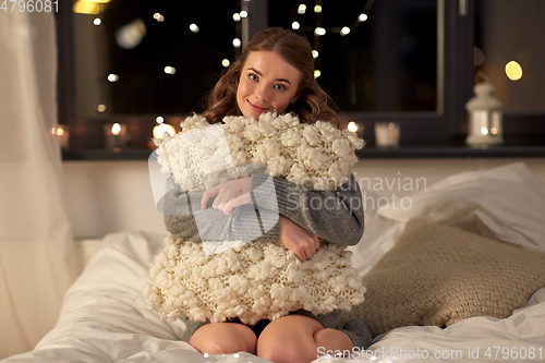 Image of happy young woman with soft pillow in bed at home