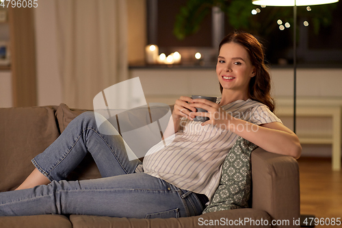 Image of smiling pregnant woman drinking tea at home