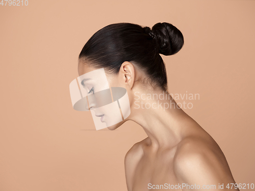 Image of Portrait of beautiful young woman isolated on brown studio background